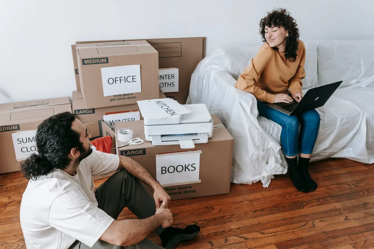 Beschriftete Bürokartons stehen neben zwei Arbeitsplätzen