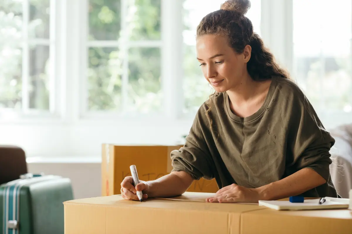 Eine Frau notiert Angaben neben gepackten Kartons