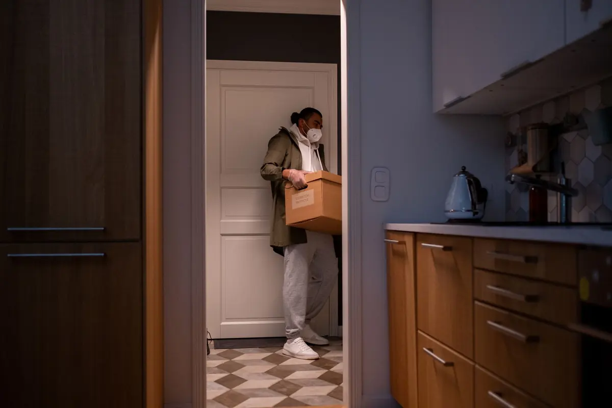Eine Person trägt einen Karton durch eine Wohnungstür