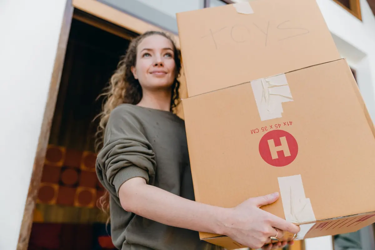 Eine Person trägt einen großen Karton durch einen Hauseingang